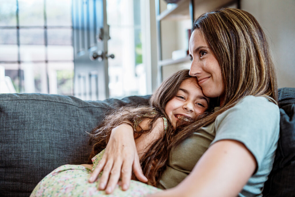 Young girl and mother hug each other on the couch Young girl and mother hug each other on the couch